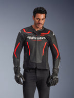 Alpinestars GP Force V2 Air Lederjacke, Motorrad-Rennjacke, Schwarz und Rot Fluo, hochwertige Lederkonstruktion mit großflächiger Perforation für optimale Belüftung, getragen von einem Model mit schwarzen Handschuhen und Hosen, mit markantem Branding und 'Racing Ahead'-Schriftzug auf der Brust