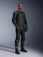 Mannelijk model in Alpinestars Missile V3 leren broek en bijpassende zwarte leren jas met gouden accenten, zwarte GP Pro racehandschoenen en zwarte racelaarzen, complete motorrace-uitrusting voor weggebruik, studio-opname.