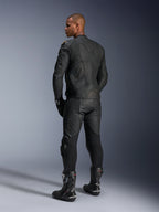 Alpinestars Missile V3 leren broek en Dusk leren jas, zwart met gouden accenten, achteraanzicht van de rijder, met logo's in reliëf en accordeon stretchpanelen, gedragen met zwarte Supertech R laarzen en handschoenen, professionele motorsportkleding.