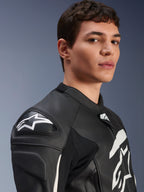 Blouson en cuir Alpinestars GP Plus V4, noir et blanc, porté par un mannequin homme, avec logo Alpinestars blanc et sliders d'épaule DFS, construction en cuir dérivée de la course pour la conduite sportive