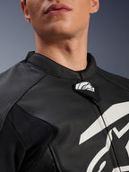 Blouson en cuir Alpinestars GP Plus V4, blouson de moto sport, noir et blanc, gros plan sur le col en cuir texturé et la languette du logo Alpinestars, graphique blanc sur la poitrine, design dérivé de la course
