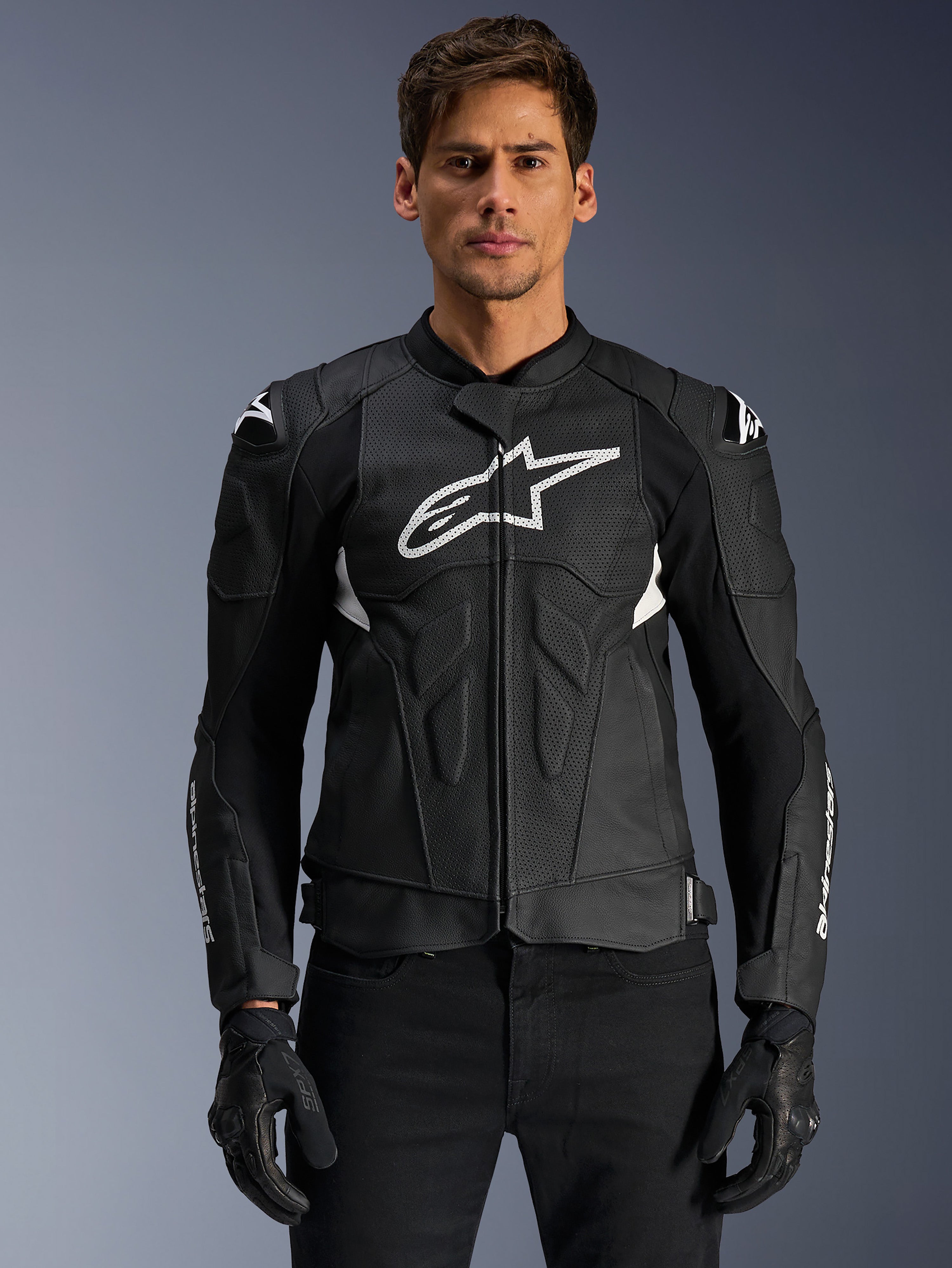Veste en cuir Alpinestars Dusk Airflow, noir et blanc, veste de moto en cuir portée par un mannequin, avec panneaux en cuir perforé pour la ventilation, un grand logo blanc sur la poitrine et des sliders d'épaule externes.