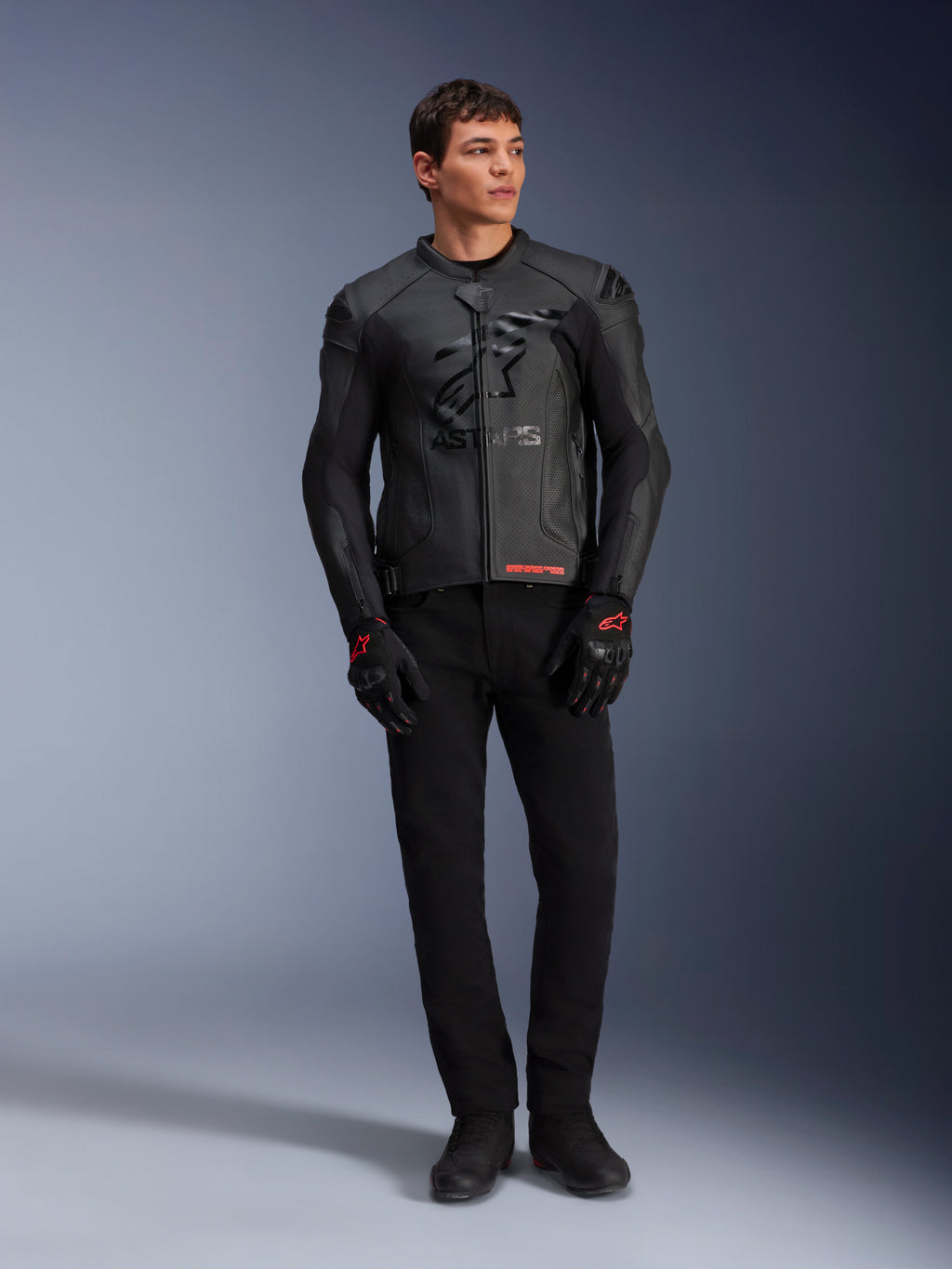 Alpinestars GP Plus R V4 Airflow Lederjacke, Schwarz, getragen von einem männlichen Model mit passenden schwarzen Handschuhen und Hosen, mit perforierten Lederbahnen, großem tonalen Stern-Logo auf der Brust und schlanker sportlicher Passform