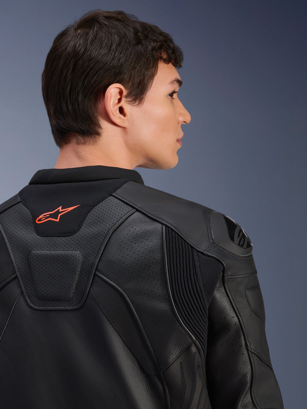 Alpinestars GP Plus R V4 Airflow Lederjacke, Schwarz, Nahaufnahme der Rückansicht an einem Model, mit perforiertem Leder in Rennsportqualität, technischen Stretch-Einsätzen und einem kleinen orangen Alpinestars-Logo am Kragen, professionelle Motorradbekleidung