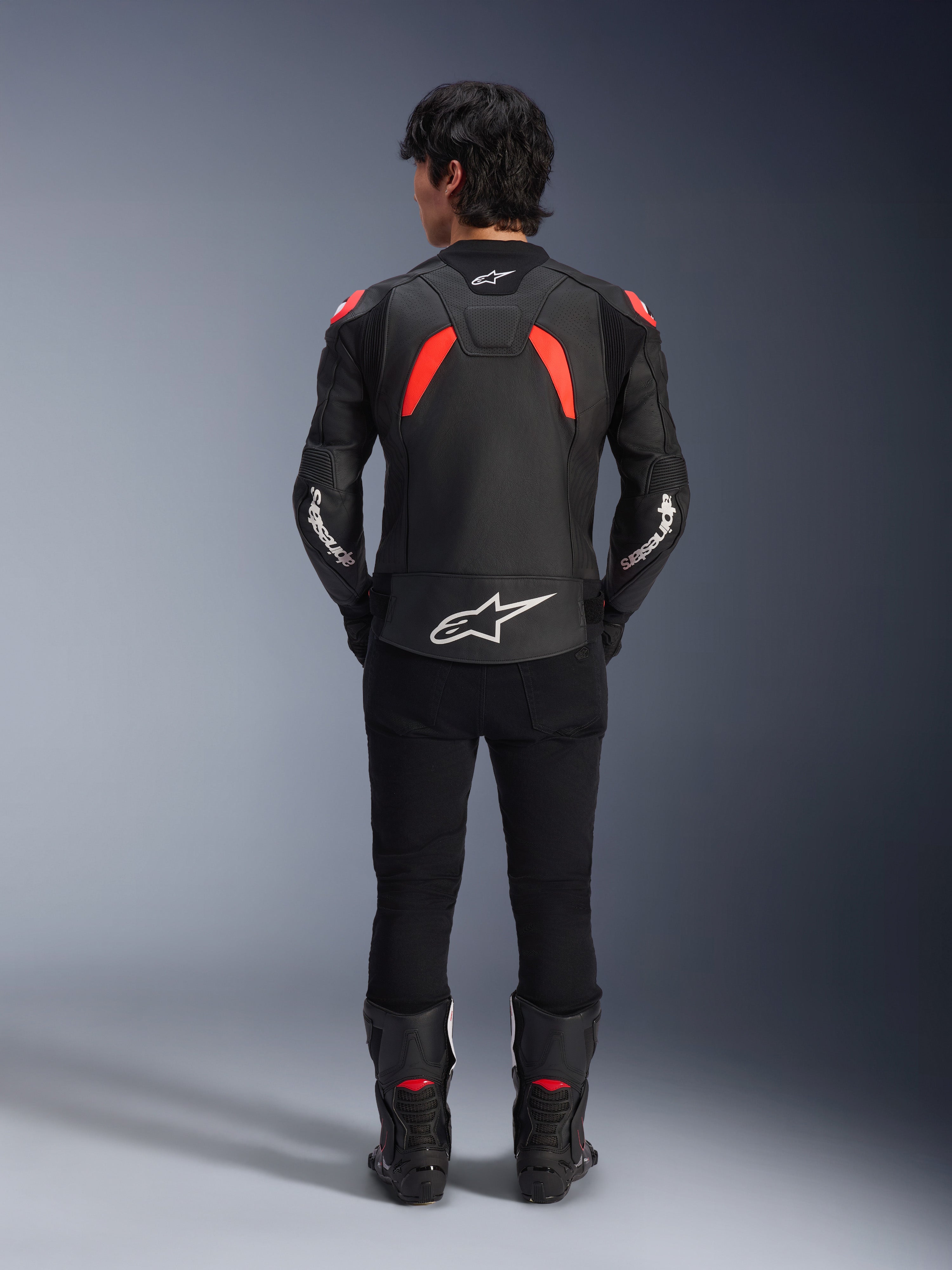 Alpinestars GP Plus R V4 Airflow Lederjacke, Schwarz, Rot Fluo und Weiß, Rückansicht an einem Model, mit perforierten Lederbahnen und markantem weißem Branding, kombiniert mit schwarzer Motorradhose und Stiefeln.