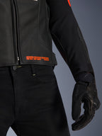 Alpinestars GP Plus R V4 Airflow Lederjacke, Nahaufnahme von Taille und Ärmel, schwarzes perforiertes Leder mit leuchtend rotem Text-Branding 'Advanced Racewear Engineering', kombiniert mit schwarzer Fahrhose und SPX 7 Motorradhandschuh