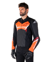 Alpinestars Faster V3 Leren Jas, zwart en fluo rood, premium sportief motorjack met witte en rode accenten, Alpinestars-branding op de borst en mouwen, gedragen met zwarte motorhandschoenen en broek.