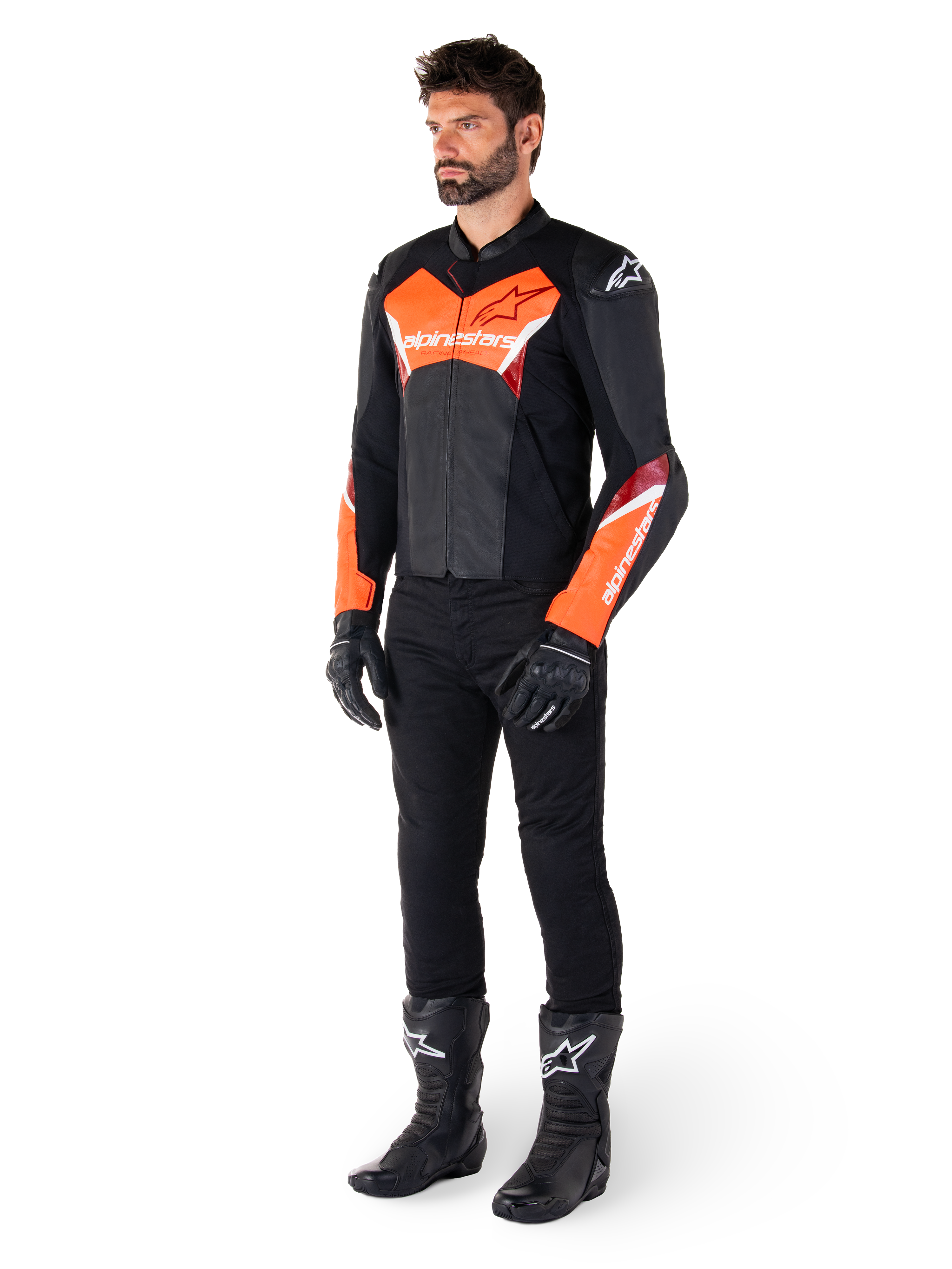 Männlicher Fahrer in der Alpinestars Faster V3 Lederjacke in Schwarz und Rot Fluo, kombiniert mit schwarzer Motorradhose, Handschuhen und Stiefeln. Die Jacke zeichnet sich durch eine vom Rennsport abgeleitete Silhouette mit markanten fluoreszierenden roten Akzenten an Brust und Ärmeln, weißem Alpinestars-Branding und einer hochwertigen Lederkonstruktion aus.