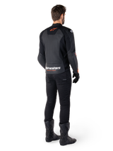 Alpinestars Faster V3 Leren Jas, sportieve motorjas, zwart met rood fluo, achteraanzicht gedragen met zwarte broek en zwarte laarzen, met 'alpinestars RACING AHEAD' tekst op de onderrug en een klein rood sterlogo, strakke sportieve leren constructie