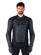 Alpinestars Faster V3 Lederjacke, schwarze Motorradjacke, Premium-Leder mit HRSF-Stretcheinsätzen, schlanke sportliche Passform, verstärkte Schultern mit Protektoren, getragen mit schwarzen Handschuhen, professionelle Ausrüstung für Straßenfahrten