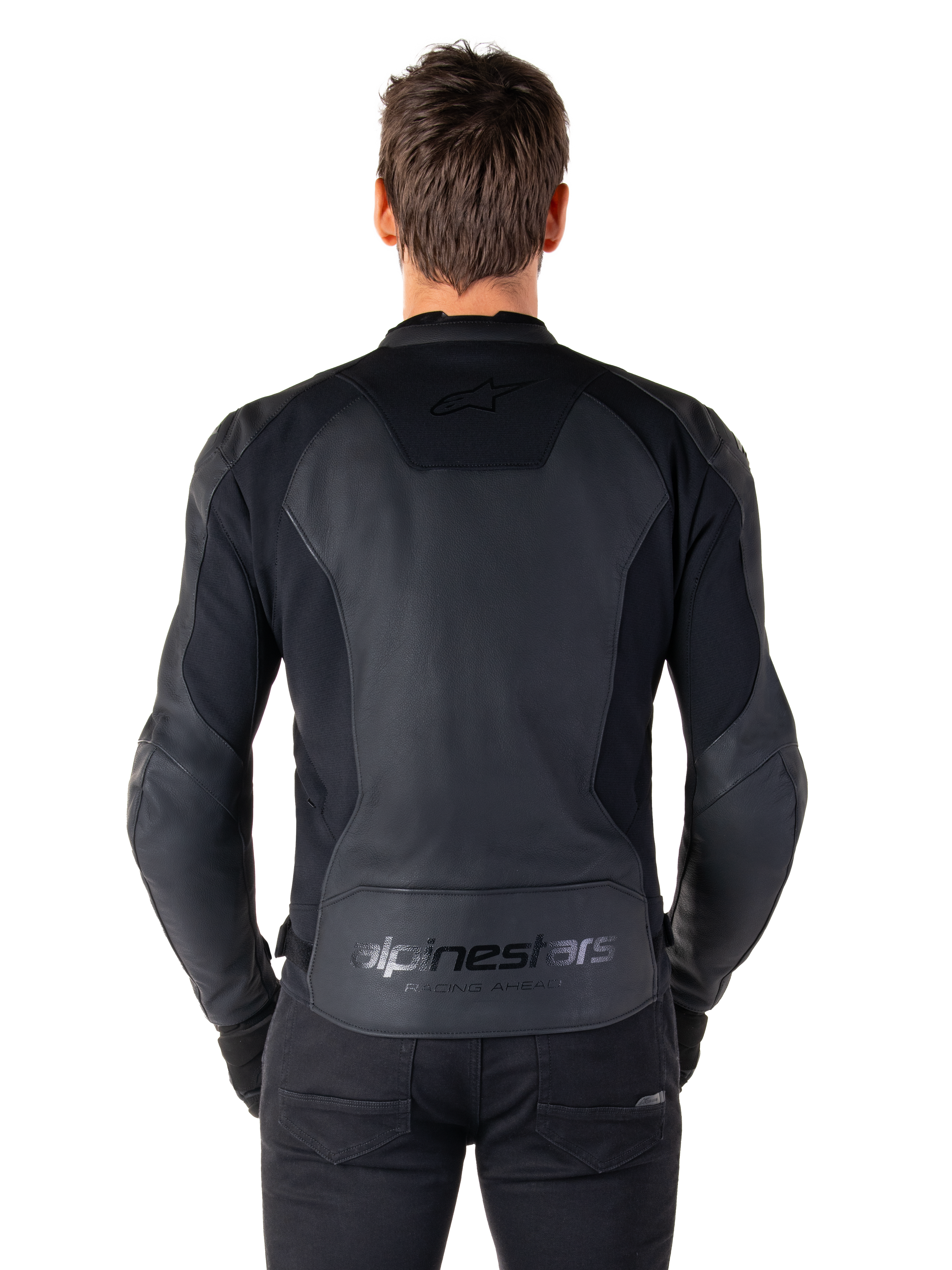 Rückansicht eines Mannes in der Alpinestars Faster V3 Lederjacke in Schwarz, mit hochwertigen Lederbahnen und flexiblen Stretcheinsätzen, dezentes „alpinestars“- und „RACING AHEAD“-Branding am unteren Rücken, sportliche Passform für Motorradfahrer