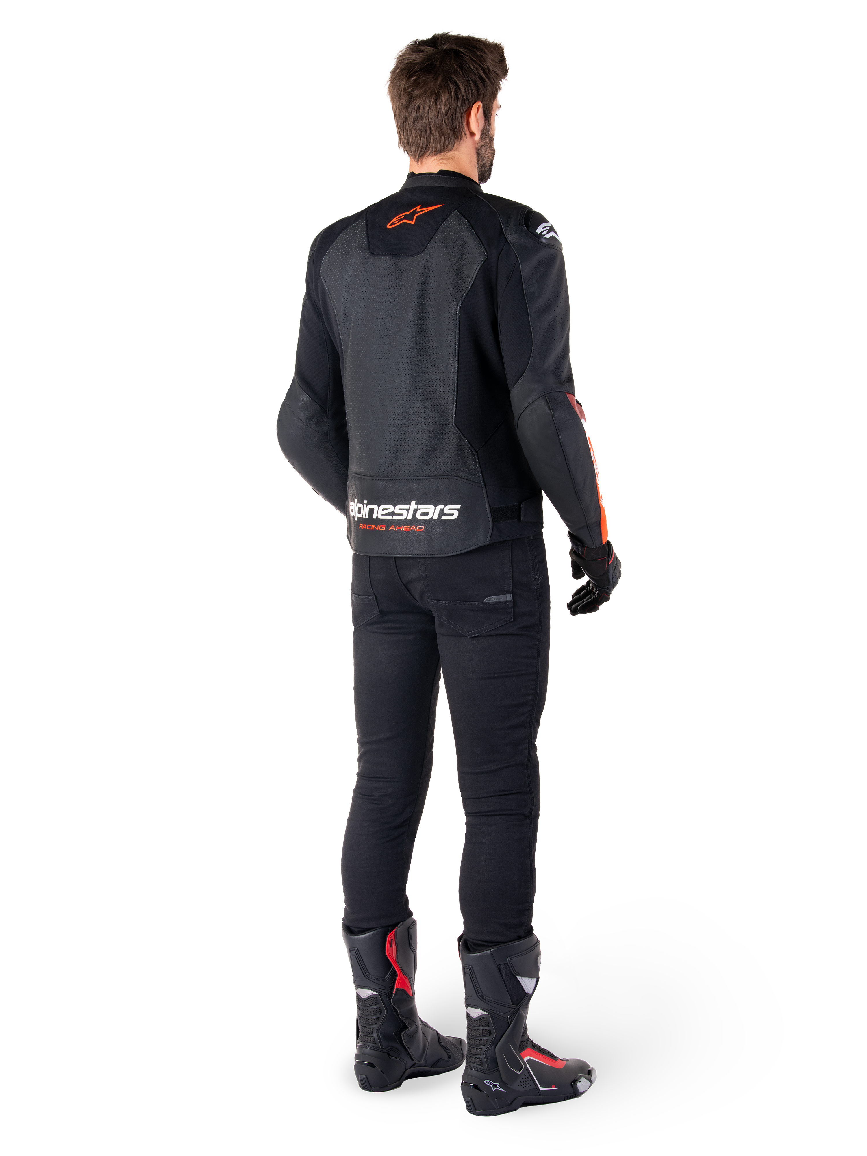 Veste en cuir Alpinestars Faster V3 Airflow, noir et rouge fluo, vue de dos sur un pilote, avec des panneaux en cuir perforé et un marquage distinctif, portée avec un pantalon noir et des bottes de moto, tenue de pilotage sportive.