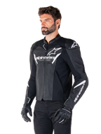 Alpinestars Faster V3 Airflow Leather Jacket, veste de moto sportive, noir et blanc avec panneaux en cuir perforé, logo Alpinestars blanc sur la poitrine et les bras, portée par un mannequin avec gants et pantalon noirs, équipement de pilotage élégant et protecteur