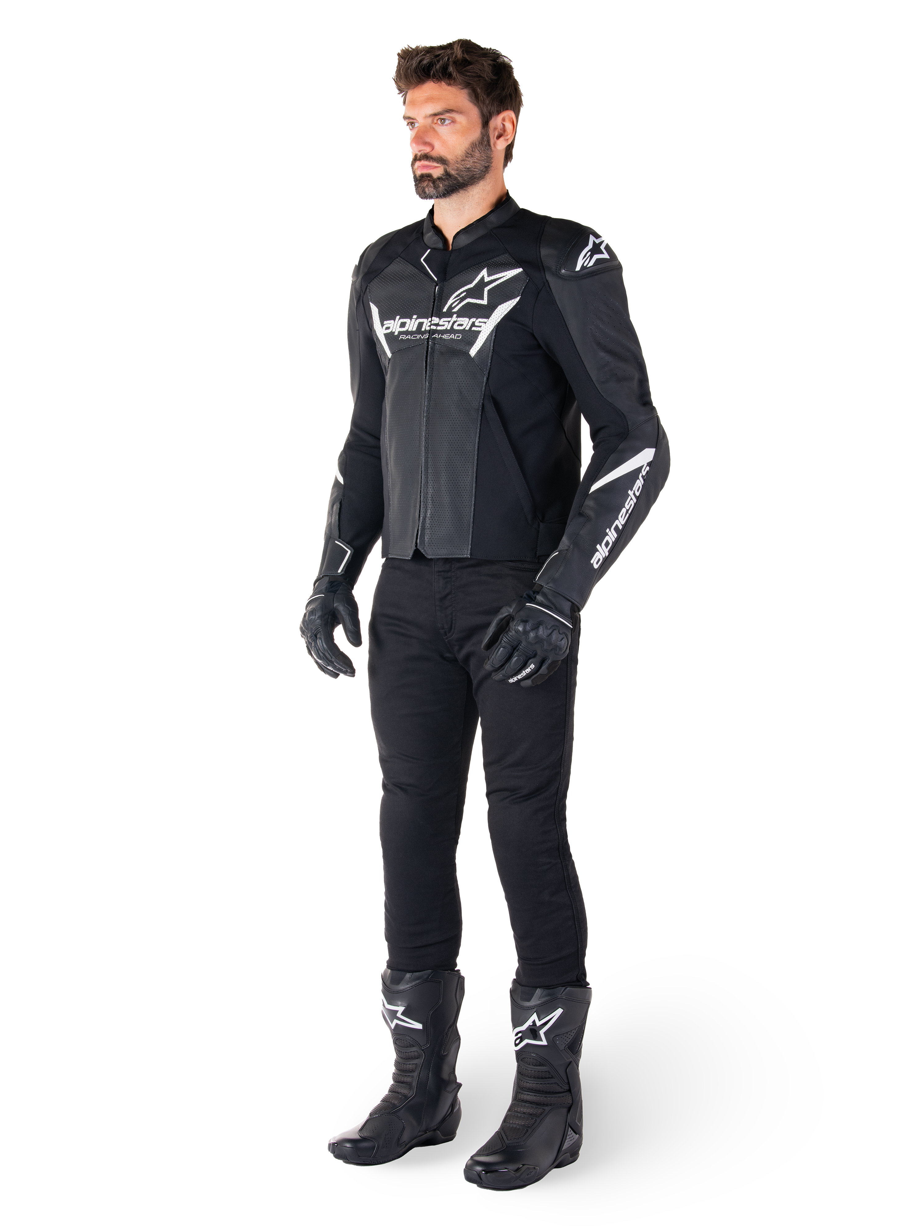 Modèle portant une veste en cuir Alpinestars Faster V3 Airflow, noir et blanc, avec cuir perforé et logos Alpinestars blancs, associée à un pantalon, des gants et des bottes de moto noirs, équipement de moto de sport