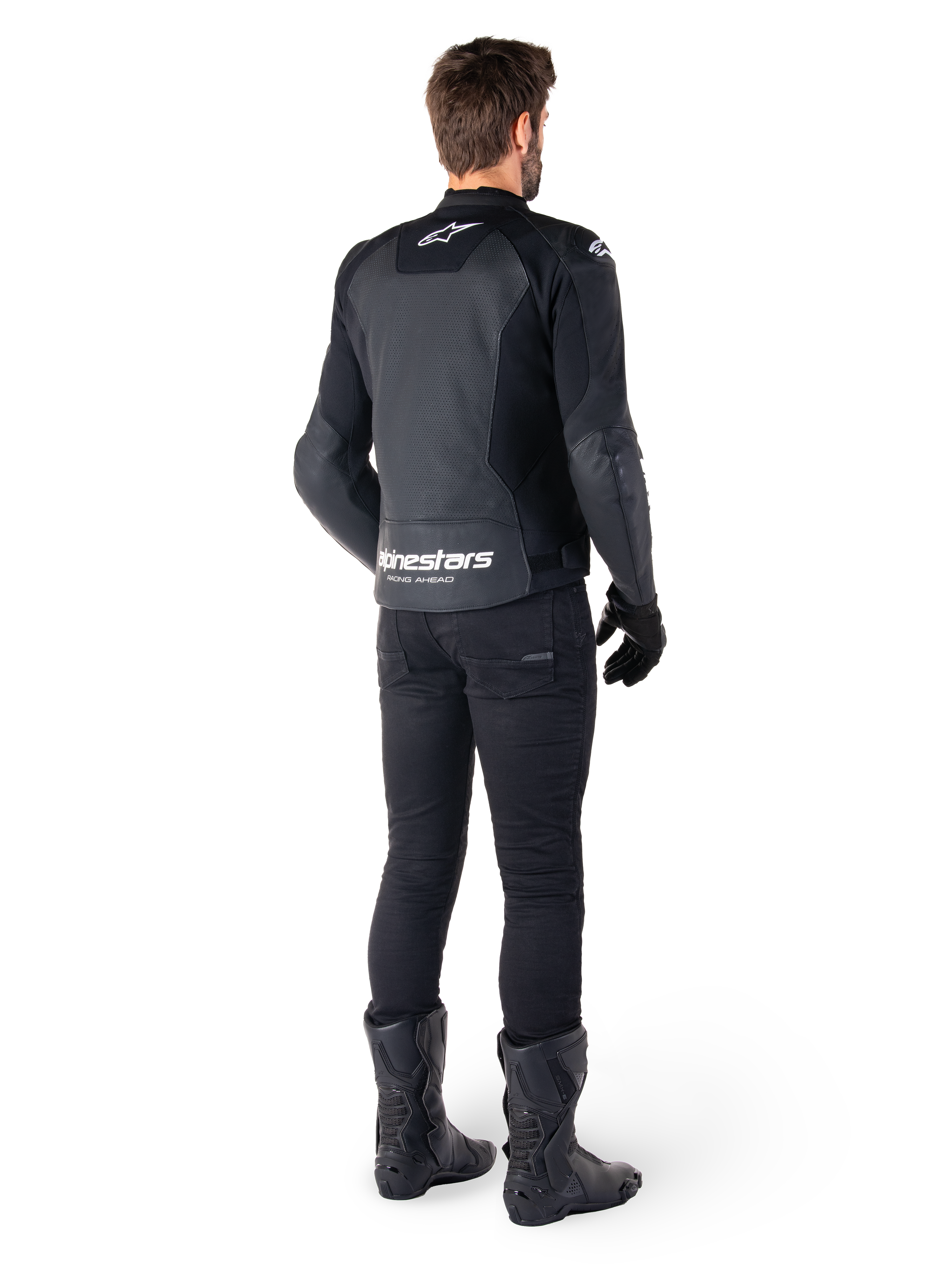 Veste en cuir Alpinestars Faster V3 Airflow, noir et blanc, vue arrière montrant les panneaux en cuir perforé et le logo Alpinestars distinctif sur le bas du dos, portée par un pilote avec un pantalon de moto, des gants et des bottes noirs.