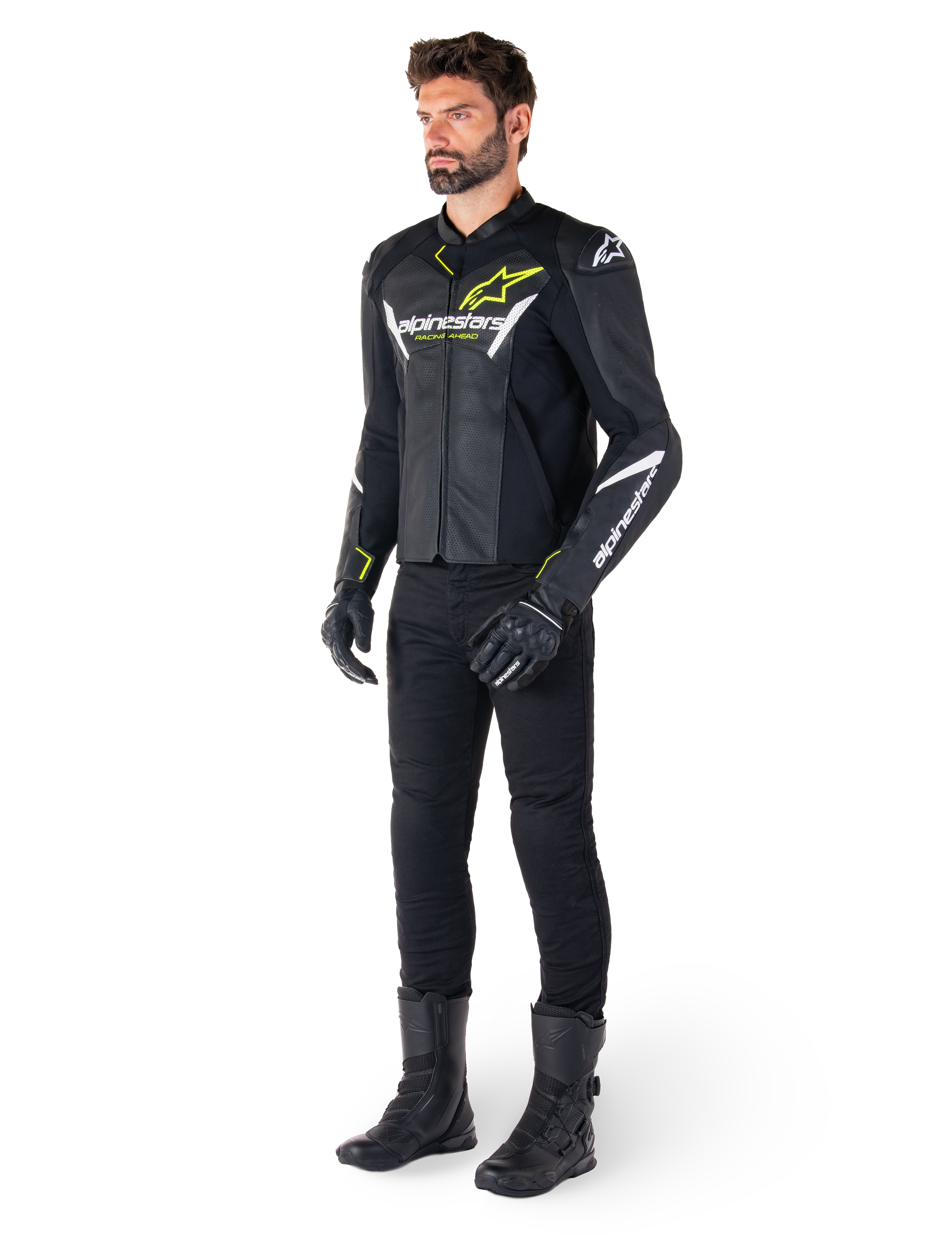 Motard portant la veste en cuir Alpinestars Faster V3 Airflow en noir, blanc et jaune fluo, avec pantalon et bottes de moto noirs, présentant des panneaux en cuir perforé, des logos blancs et des touches jaune fluo, équipement de pilotage sportif professionnel