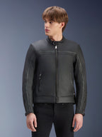 Blouson en cuir Alpinestars Dyno, noir, blouson de moto en cuir de bovin de qualité supérieure, porté par un mannequin avec un pantalon noir, design d'inspiration classique avec fermeture éclair centrale et col montant discret, vêtement de moto urbain contemporain.