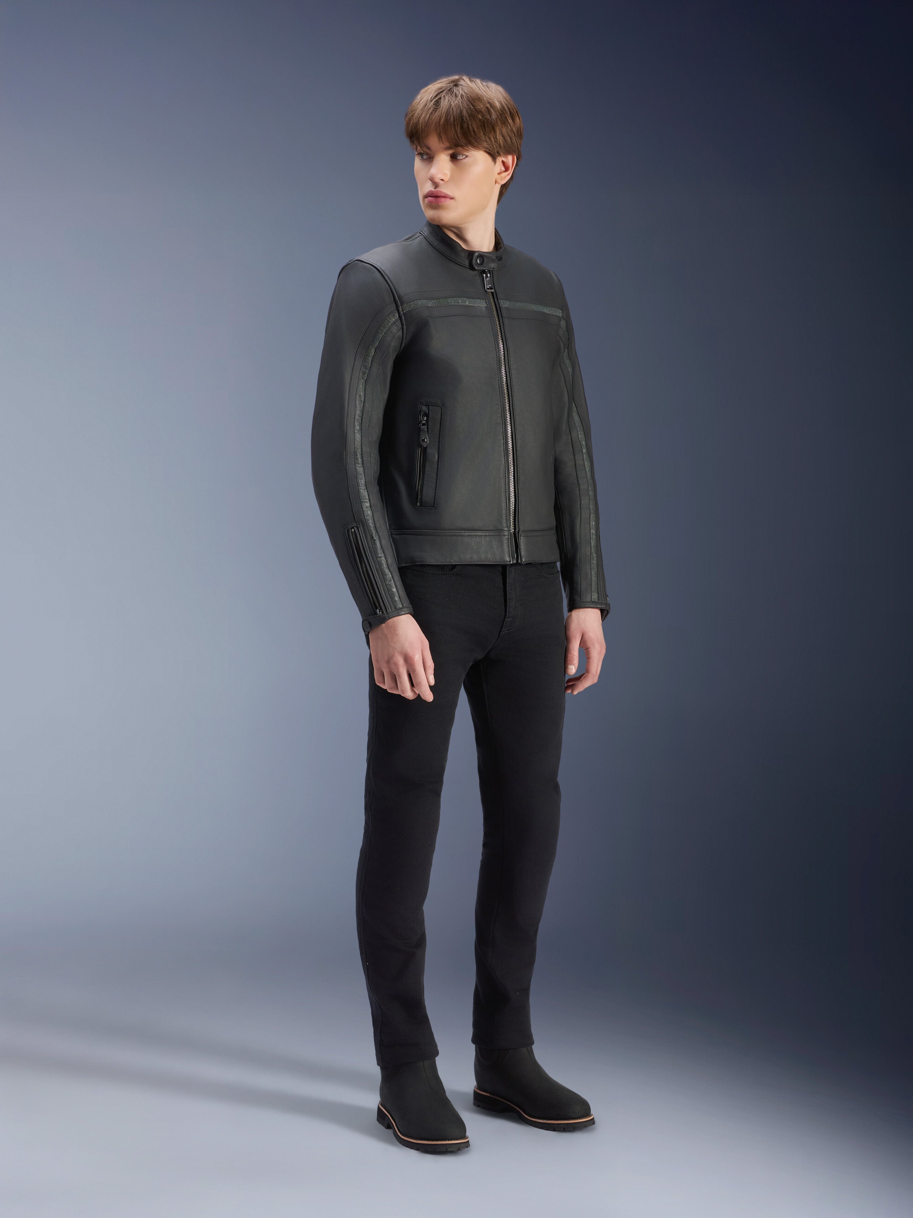 Blouson en cuir Alpinestars Dyno en Noir, veste de moto en cuir de bovin de première qualité, portée par un mannequin homme avec un pantalon slim noir et des bottes noires, design minimaliste d'inspiration héritage pour la conduite urbaine contemporaine, décor de studio.