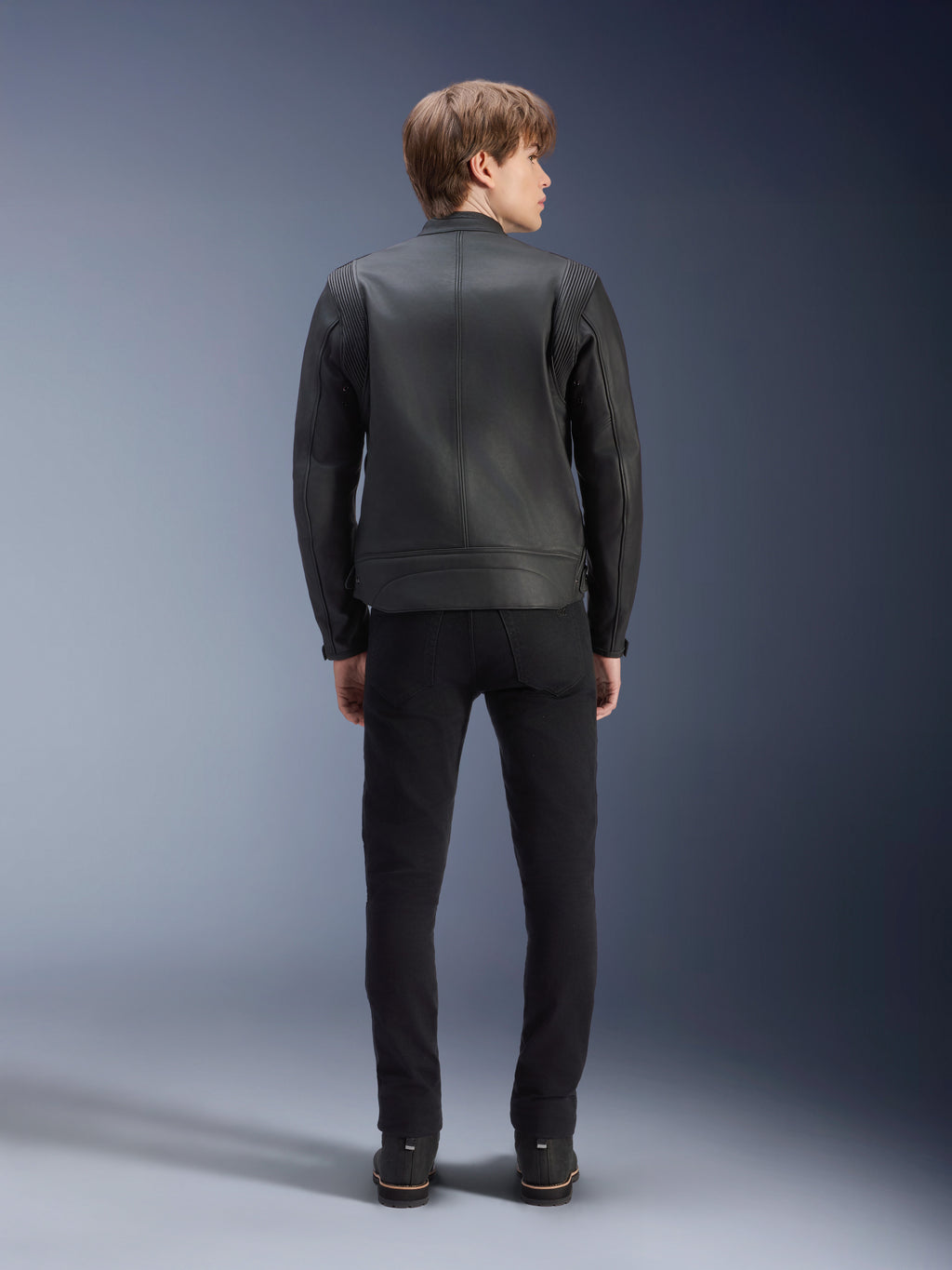 Blouson en cuir Alpinestars Dyno, noir, vue de dos sur mannequin, cuir de bovin de qualité supérieure avec panneaux en accordéon aux épaules, blouson de moto d'inspiration héritage, porté avec un pantalon et des bottes noirs, style urbain contemporain