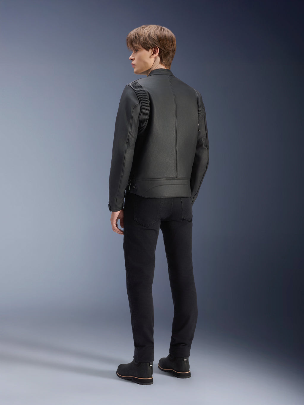 Blouson en cuir Alpinestars Dyno, noir, porté par un mannequin homme, vue de dos, doté d'empiècements côtelés aux épaules, associé à un pantalon et des bottes noirs, style moto urbain d'inspiration héritage.