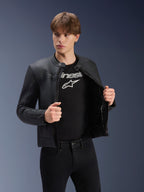 Blouson en cuir Alpinestars Dyno, noir, porté par un mannequin homme sur un t-shirt noir à logo, blouson de moto en cuir de bovin haut de gamme au design d'inspiration héritage, doté de rayures discrètes sur la poitrine et d'une coupe urbaine contemporaine.