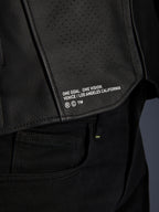 Close-up van de Alpinestars Atem V5 leren jas in het zwart, met het onderste rugpaneel voorzien van 'ONE GOAL. ONE VISION. VENICE / LOS ANGELES CALIFORNIA' branding en een geperforeerde leerstructuur.