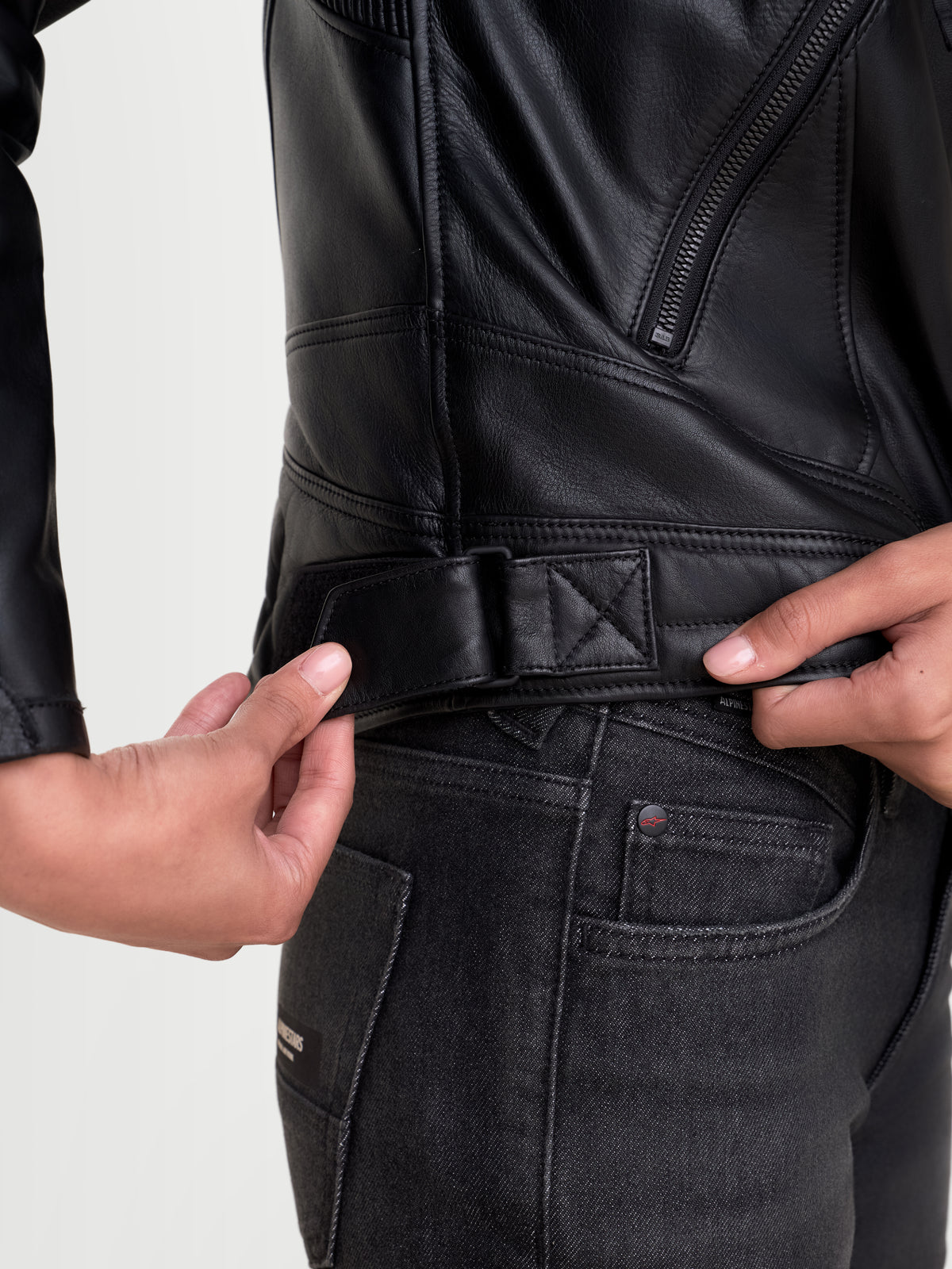 Revea Femme Veste en cuir Alpinestars, blouson de moto urbain noir pour femme, vue en gros plan de la patte de réglage de la taille et de la construction en cuir de bovin pleine fleur portée par un modèle