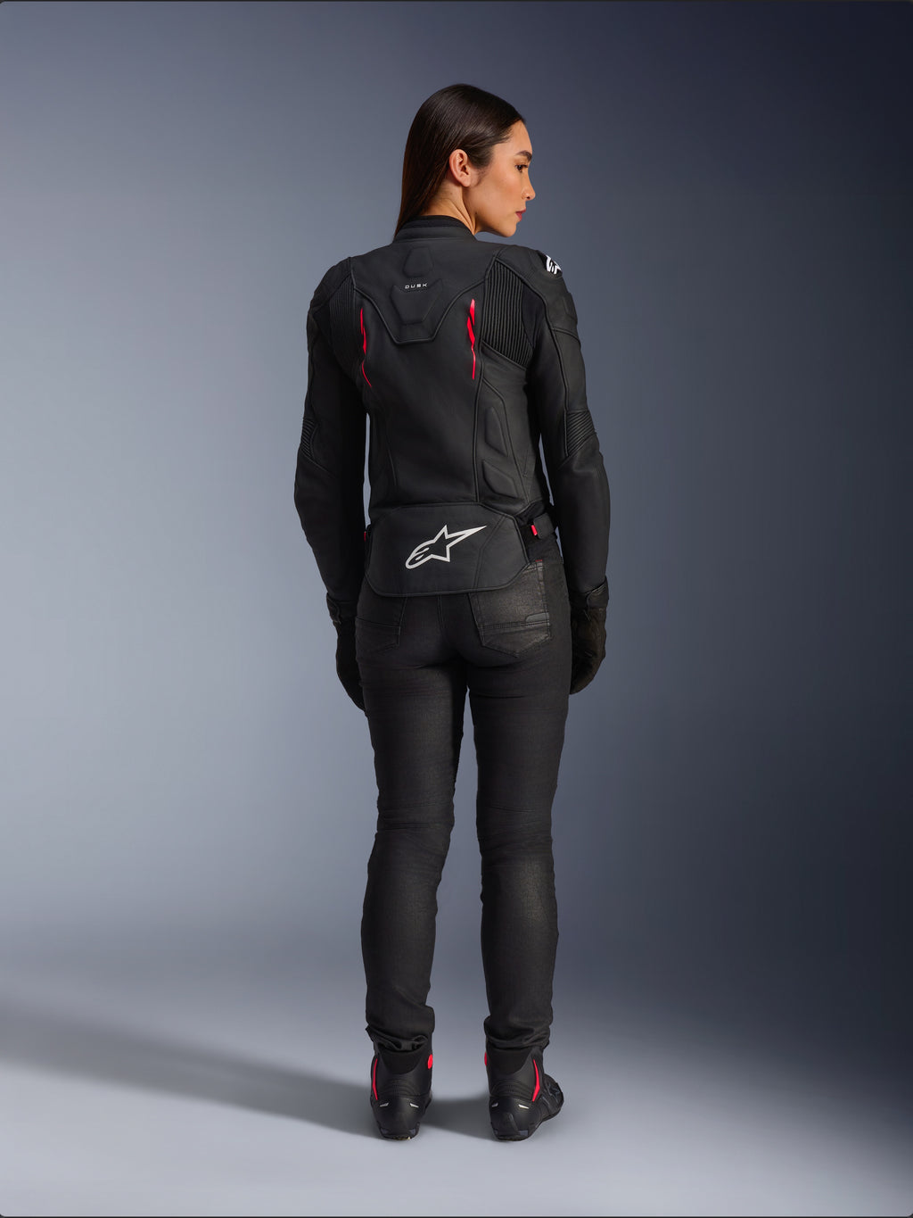 Alpinestars Stella Dusk Leather Jacket, rear view, black leather with Diva Pink and White accents, features white Alpinestars logo on lower back and pink vent details, worn with black riding pants and boots, premium sport motorcycle gear for women