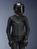 Alpinestars Stella GP Plus V4 leren damesjas in Black Black, gedragen met een zwarte carbon helm en racehandschoenen, slanke leren constructie met subtiele merknaam op de borst, getailleerd silhouet voor vrouwelijke rijders, professionele sportmotoruitrusting