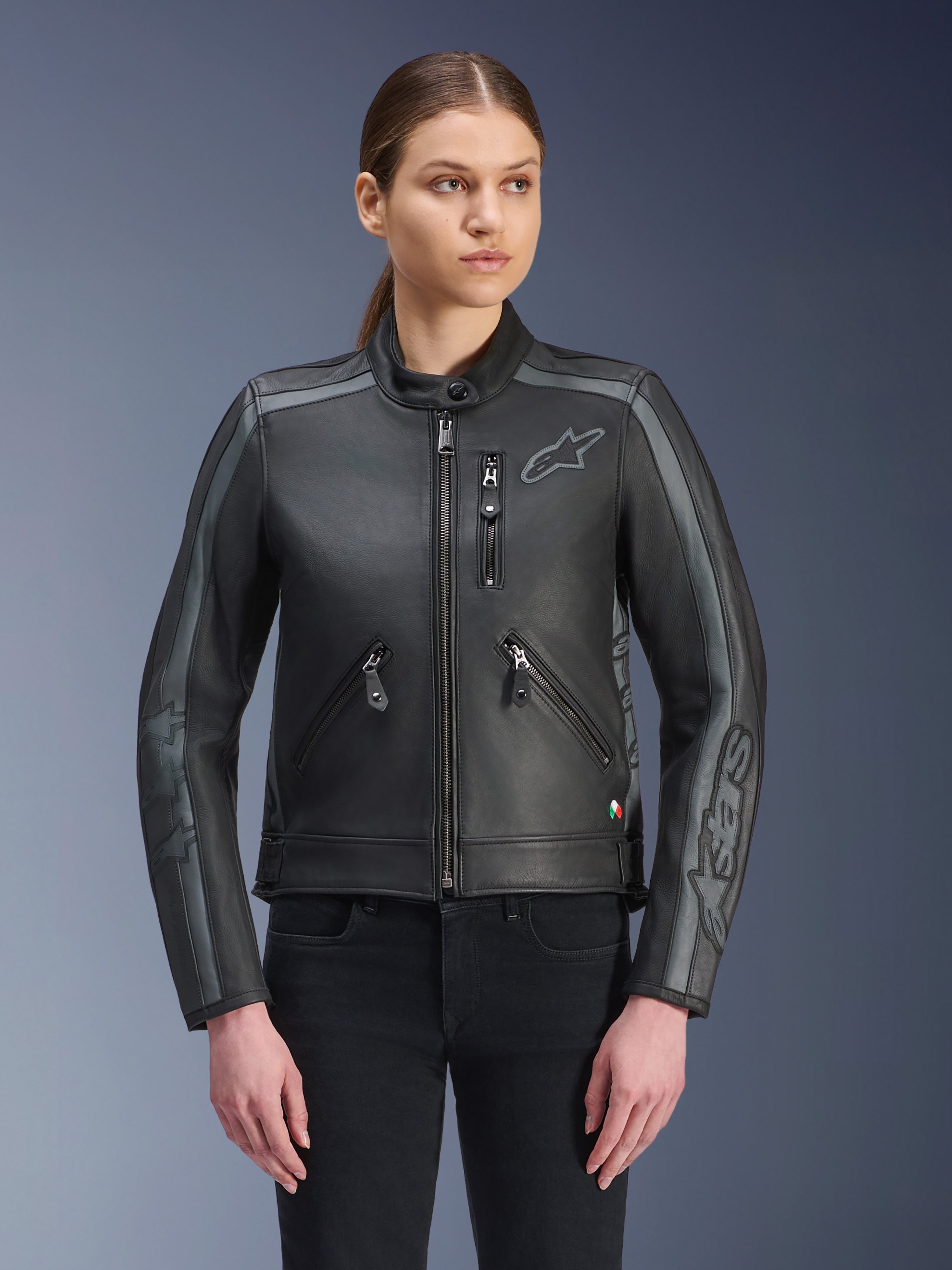 Alpinestars Stella Dyno leren motorjas, dames motorjas, zwart en tar grijs, premium runderleren constructie met grijze streepdetails op de schouders en mouwen, voorzien van ritszakken aan de voorzijde en een geborduurd logo op de borst, stijlvolle urban motoruitrusting