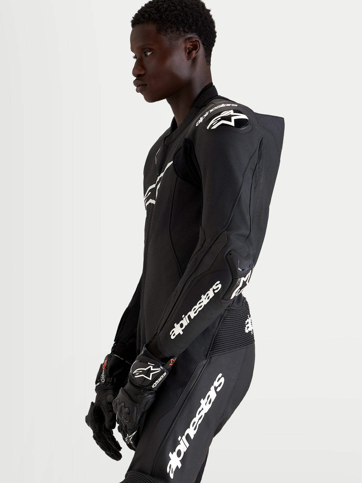 Alpinestars Missile V3, combinaison en cuir pour course moto, noire et blanche, avec bosse aérodynamique, portée par un pilote