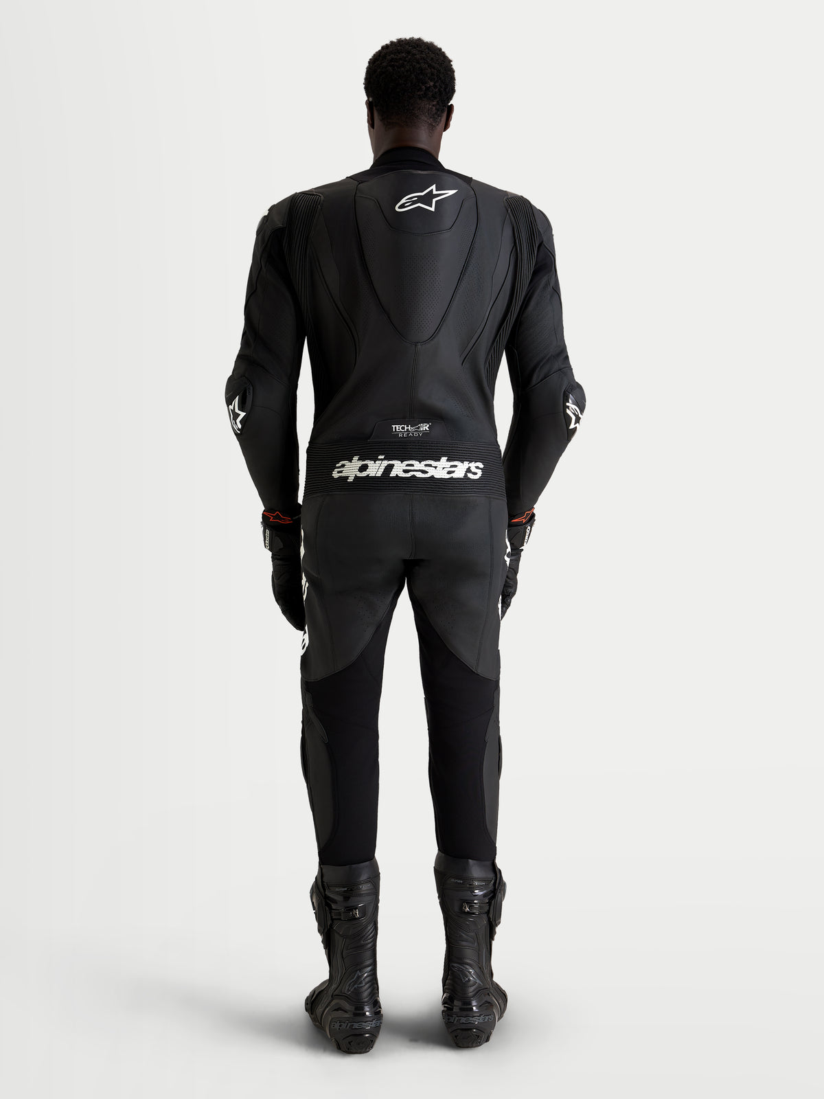 Combinaison en cuir Alpinestars Missile V3 1 Pc, combinaison moto racing pour homme, noire avec logos blancs, vue de dos d'un pilote