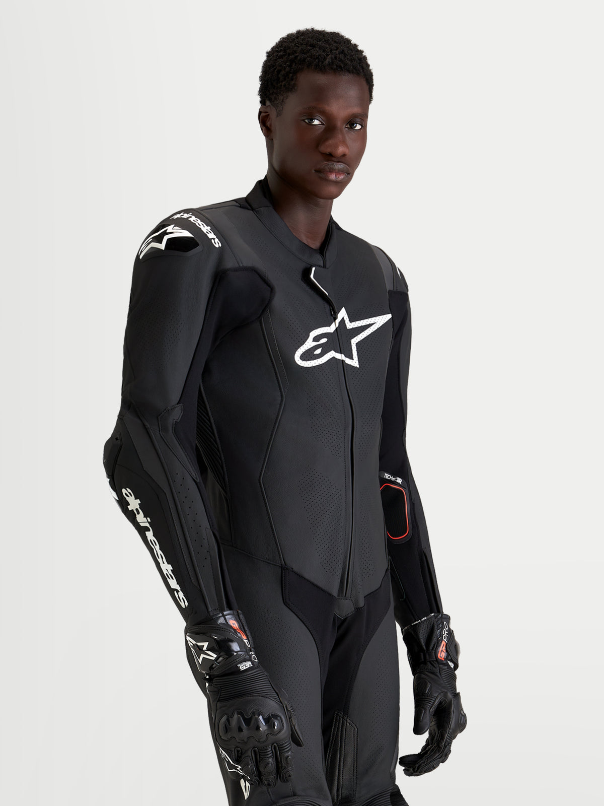 Combinaison en cuir Missile V3 1 Pc d'Alpinestars, combinaison moto pour homme noire et blanche, portée par un pilote sur fond neutre.