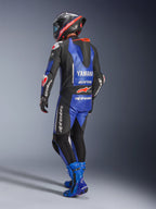 Alpinestars Yamaha GP-R7 Einteiliger Lederanzug, Metallic-Blau, Schwarz und Weiß, Rückansicht mit aerodynamischem Rennhöcker und Yamaha-Branding, getragen mit passenden blauen Rennstiefeln und Helm, professioneller Performance-Lederanzug für den Rennsport
