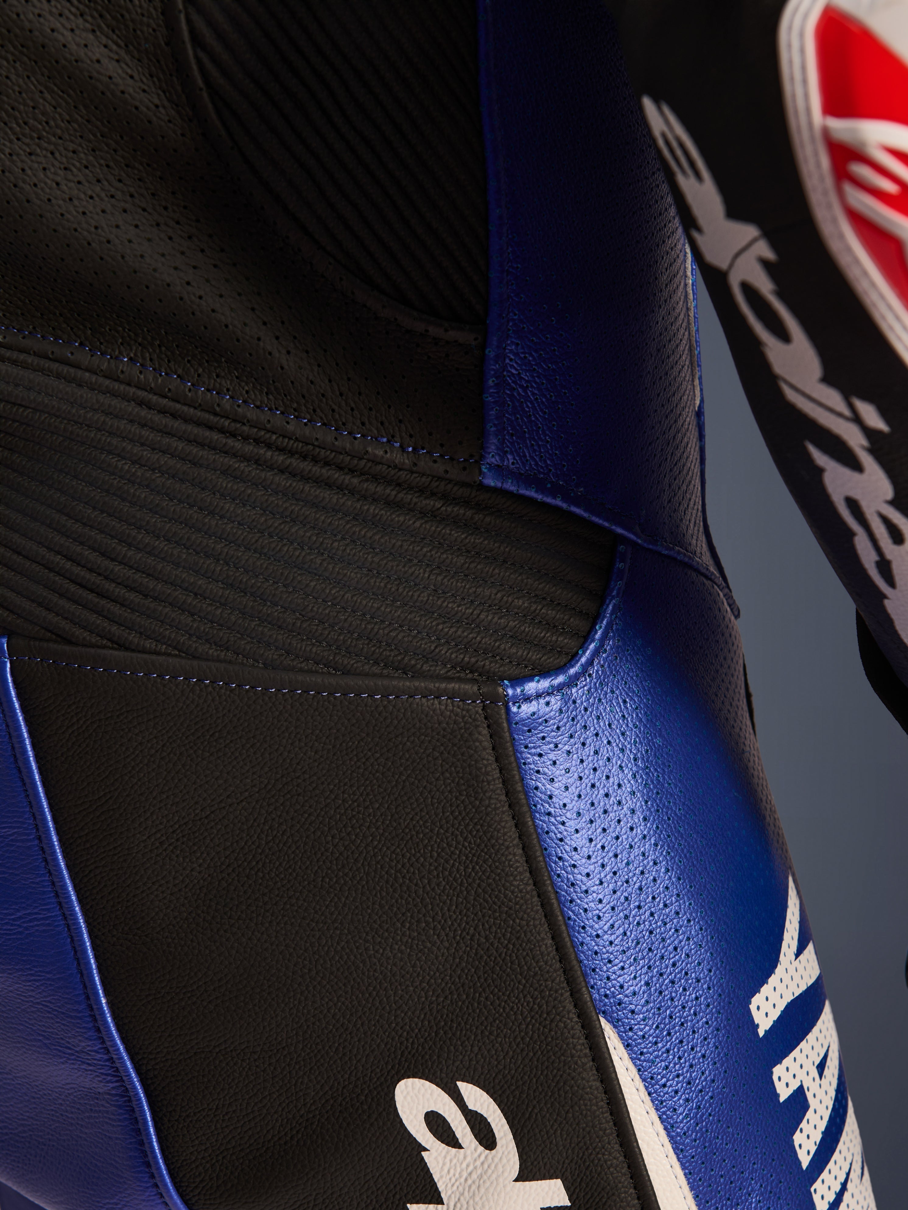 Nahaufnahme des Alpinestars Yamaha GP-R7 Einteiligen Lederanzugs, Metallic-Blau und Schwarz, mit perforierten Lederbahnen zur Belüftung, schwarzen Akkordeon-Stretcheinsätzen für Flexibilität und markantem weißem Yamaha-Branding, hochwertige Rindslederkonstruktion in Rennqualität.