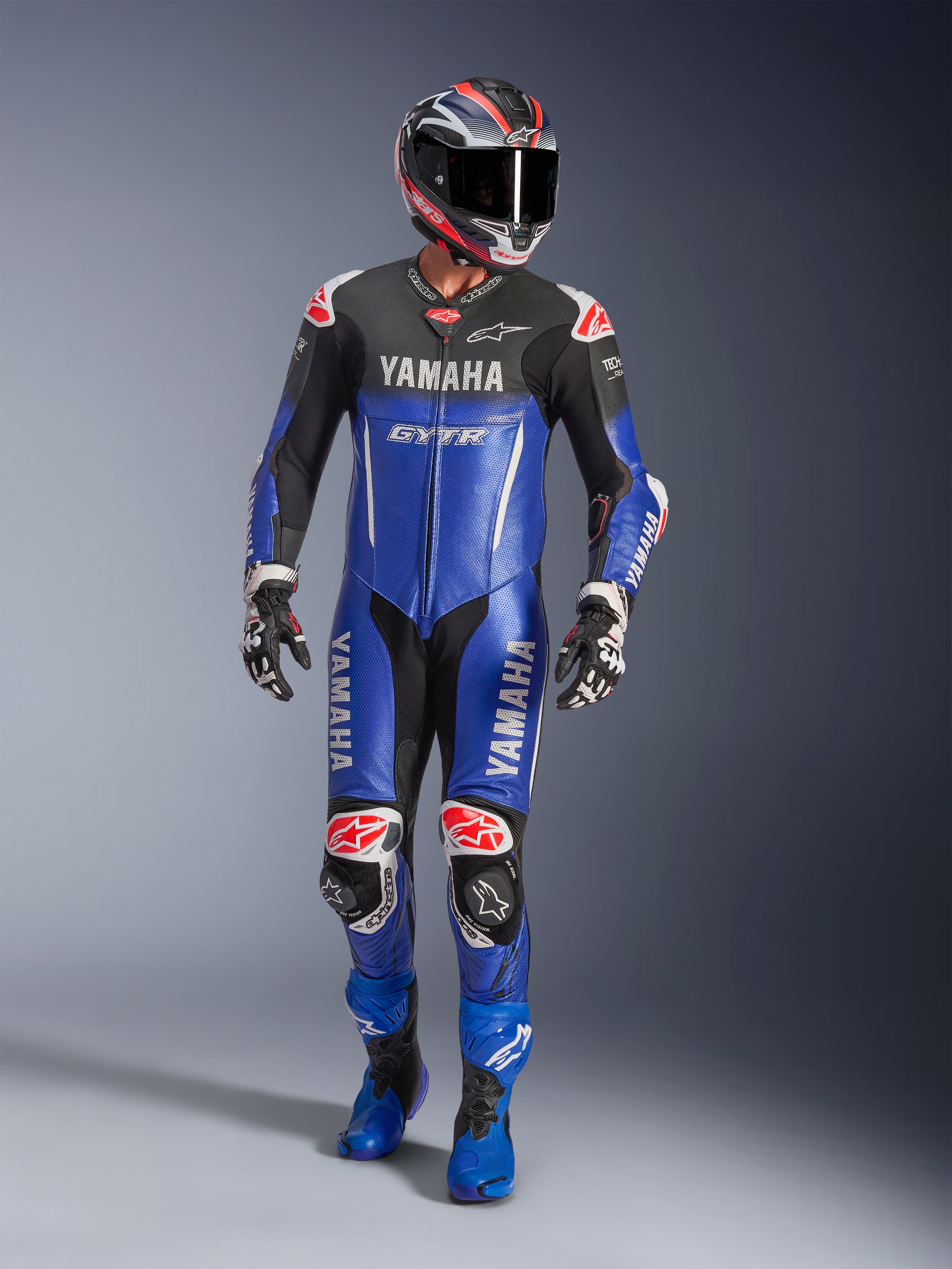 Alpinestars Yamaha GP-R7, combinaison de course une pièce en cuir, bleu métallisé et noir avec accents rouges et blancs, logos Yamaha et GYTR, portée avec casque, gants et bottes bleues assortis, équipement de performance professionnel