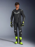 Combinaison en cuir Alpinestars GP Force V2, combinaison de course moto une pièce noire, portée avec des bottes et des gants jaune fluo, dotée de logos blancs et de cuir perforé, design ajusté pour les journées sur piste