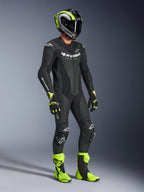 Combinaison en cuir Alpinestars GP Force V2, combinaison de moto une pièce, noire avec marquages blancs, portée avec casque, gants et bottes assortis jaune néon et noir, équipement de course haute performance pour la piste et le pilotage sportif