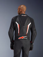 Combinaison en cuir Alpinestars GP Force V2, combinaison de moto 1 pièce, noir, blanc et rouge fluo, vue arrière du haut du corps montrant le cuir perforé et le logo Tech-Air Ready, portée avec des gants noirs et rouges assortis