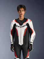 Combinaison en cuir Alpinestars GP Force V2 - 1 pièce, blanc, noir et rouge fluo, portée par un mannequin homme, avec panneaux en cuir perforé et logo Alpinestars sur la poitrine, assortie à des gants de course noirs et blancs, conçue pour la piste et la performance