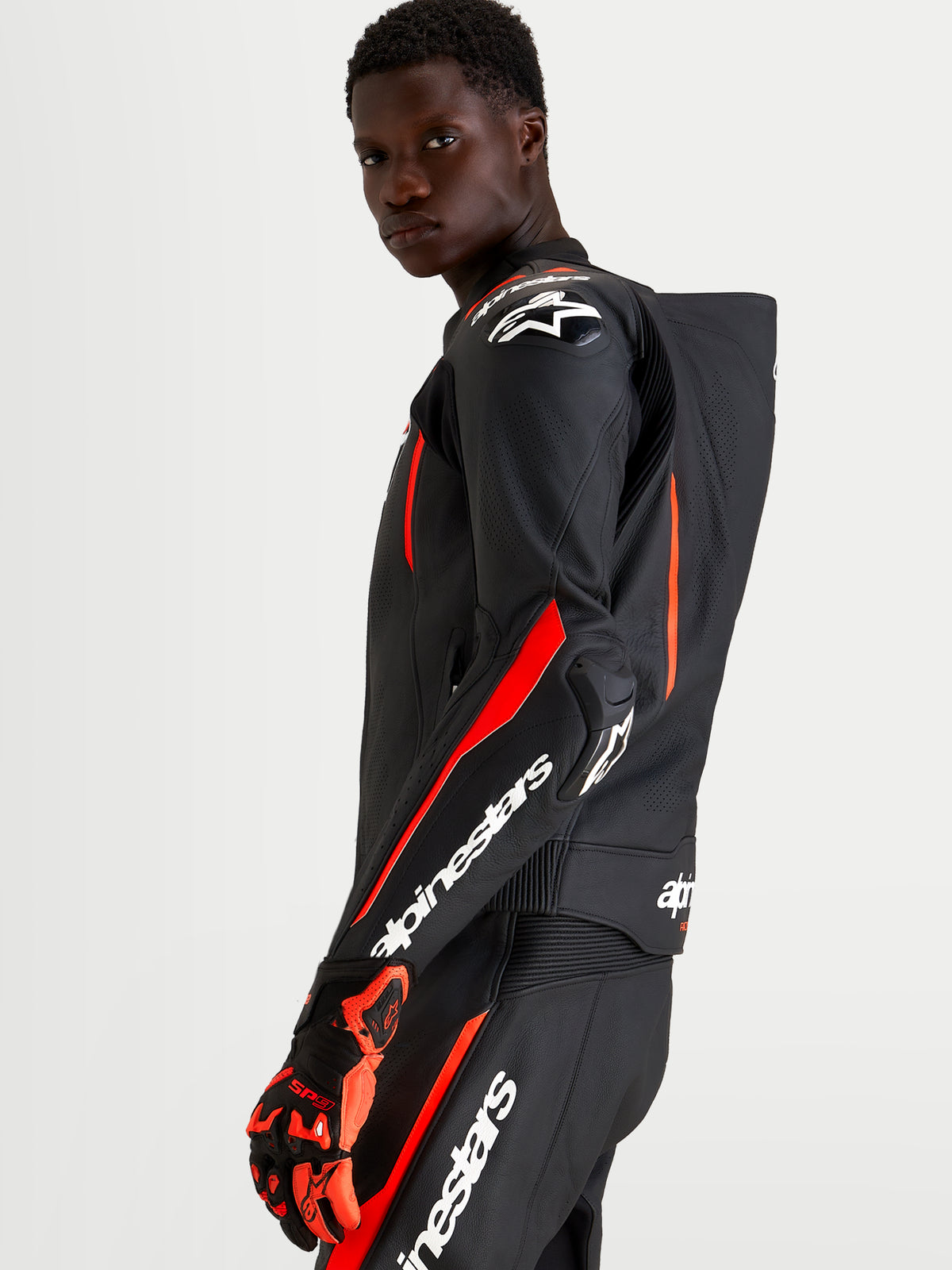 Combinaison en cuir Missile V3 2 pièces d'Alpinestars, combinaison moto racing pour homme, noire et rouge fluo avec bosse aérodynamique et protections, vue sur modèle