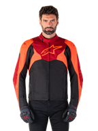 Alpinestars T-Jaws V4 Wasserdichte Jacke, Sport-Textil-Motorradjacke, Schwarz mit Red Fluo und dunkelroten Akzenten, getragen von einem männlichen Model mit passenden Handschuhen, technische Fahrerausrüstung mit markantem Stern-Logo auf der Brust.