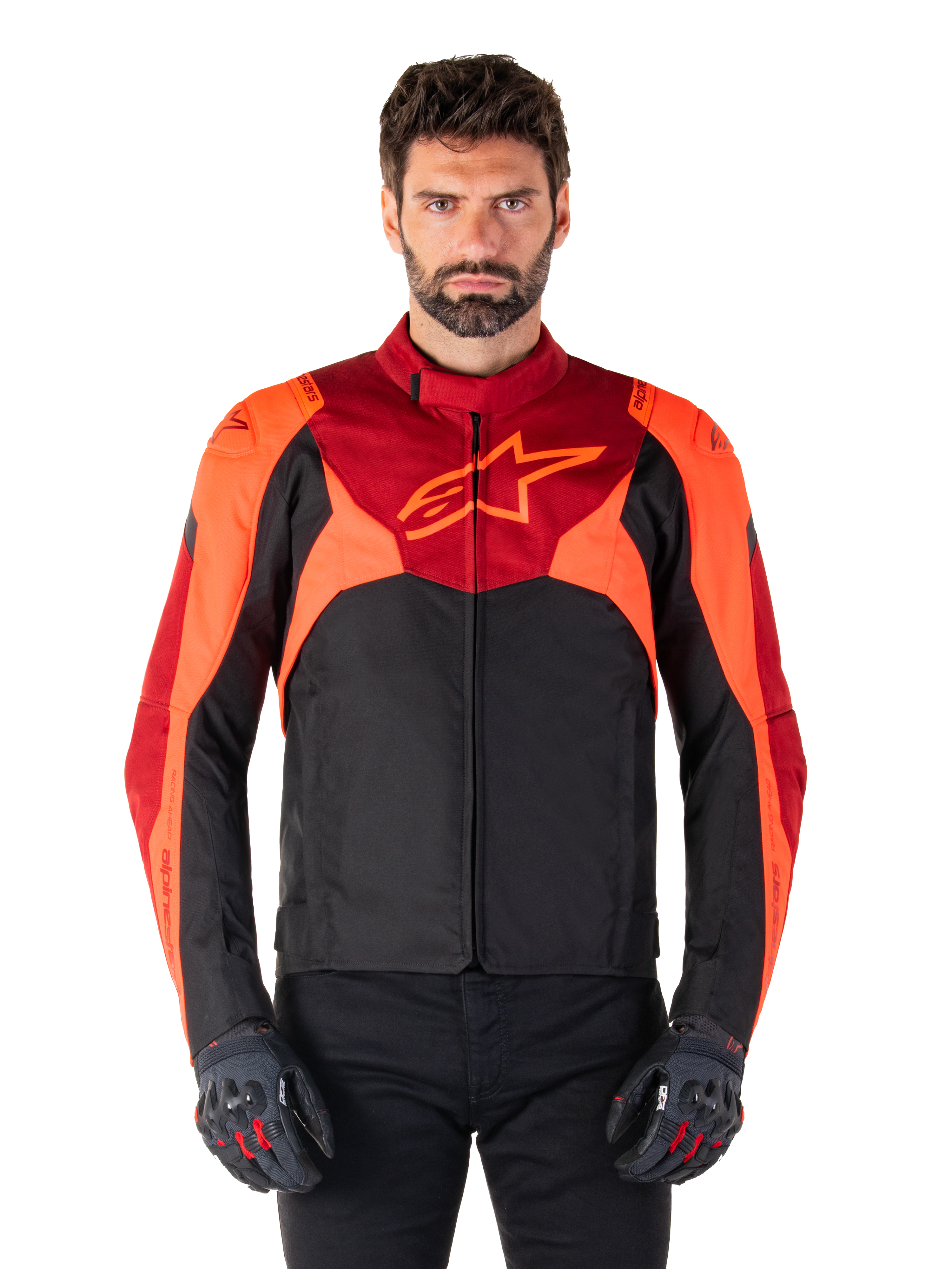 Alpinestars T-Jaws V4 Wasserdichte Jacke, Sport-Textil-Motorradjacke, Schwarz mit Red Fluo und dunkelroten Akzenten, getragen von einem männlichen Model mit passenden Handschuhen, technische Fahrerausrüstung mit markantem Stern-Logo auf der Brust.