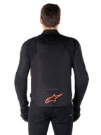 Alpinestars T-Jaws V4 Wasserdichte Jacke, Rückansicht, Schwarz mit fluoreszierendem Rot, rotes Alpinestars-Logo am unteren Rücken, technische Textilkonstruktion, getragen mit schwarzer Hose und Handschuhen für einen sportlichen Riding-Look