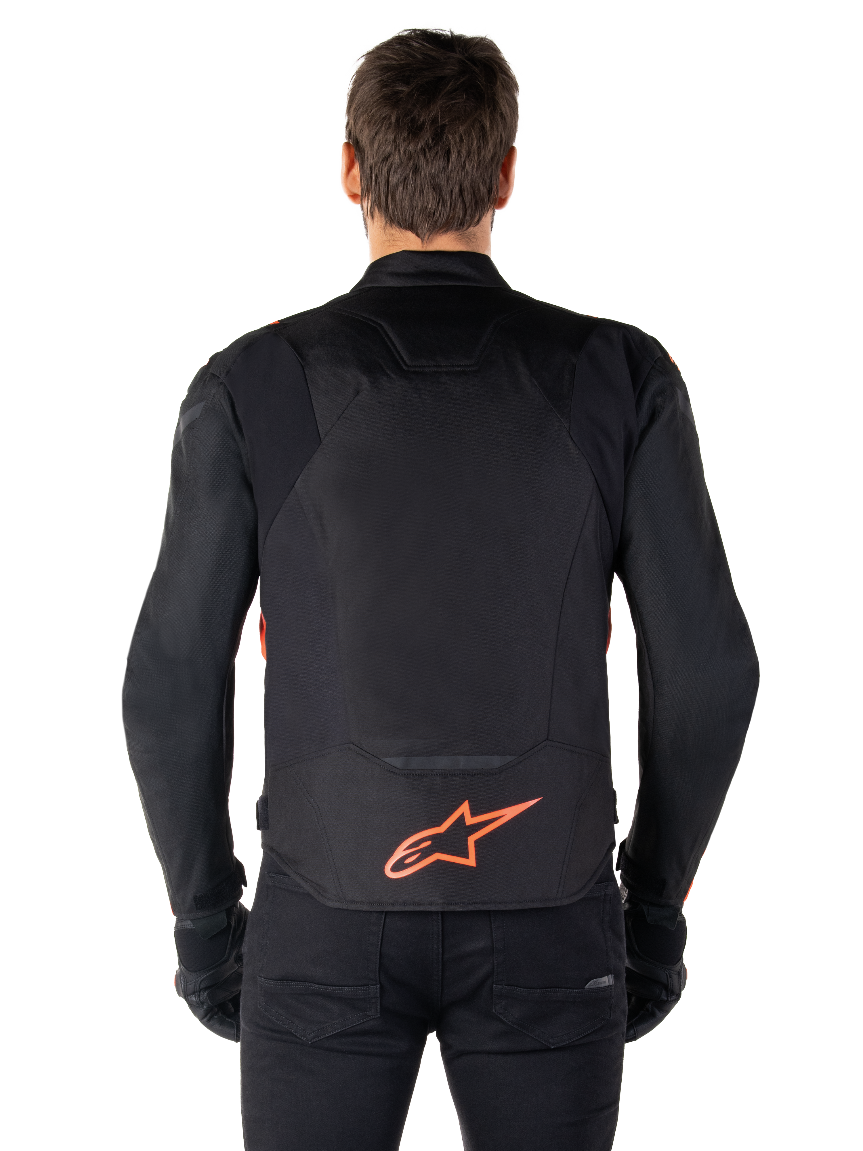 Alpinestars T-Jaws V4 Wasserdichte Jacke, Rückansicht, Schwarz mit fluoreszierendem Rot, rotes Alpinestars-Logo am unteren Rücken, technische Textilkonstruktion, getragen mit schwarzer Hose und Handschuhen für einen sportlichen Riding-Look