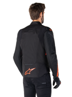 Männliches Modell in der Alpinestars T-Jaws V4 Wasserdichten Jacke in der Rückansicht, Schwarz mit Red Fluo Akzenten, mit einem Red Fluo Logo am unteren Rücken und Akzenten an den Schultern und Ärmeln, sportliche Motorradbekleidung.