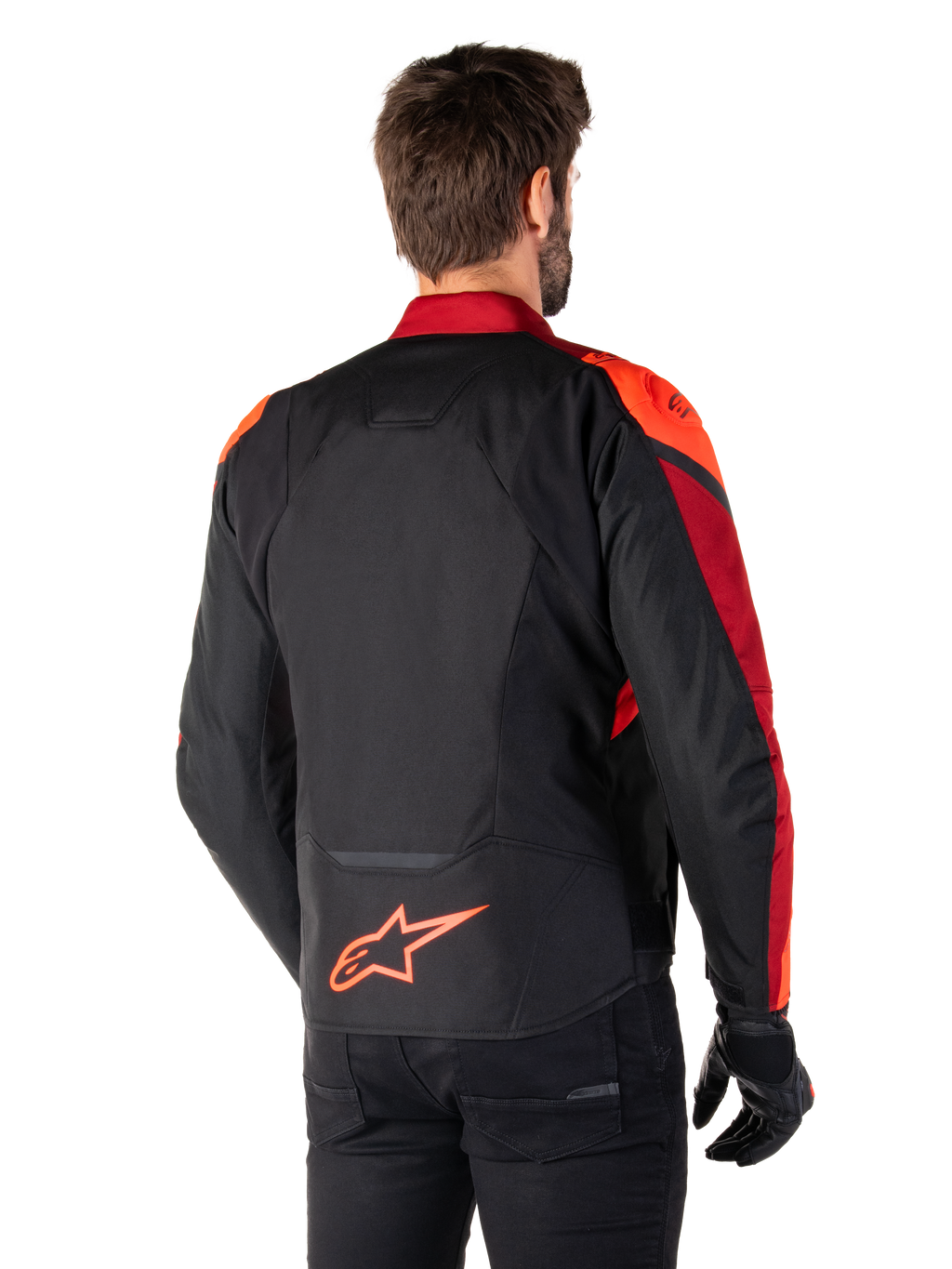Rückansicht eines Mannes, der die Alpinestars T-Jaws V4 Wasserdichte Jacke in Schwarz Rot Fluo Dunkelrot trägt, mit leuchtend roten Akzenten an den Schultern und Ärmeln, einem fluoreszierend roten Alpinestars-Logo auf dem unteren Rücken, kombiniert mit einer schwarzen Hose und Handschuhen.