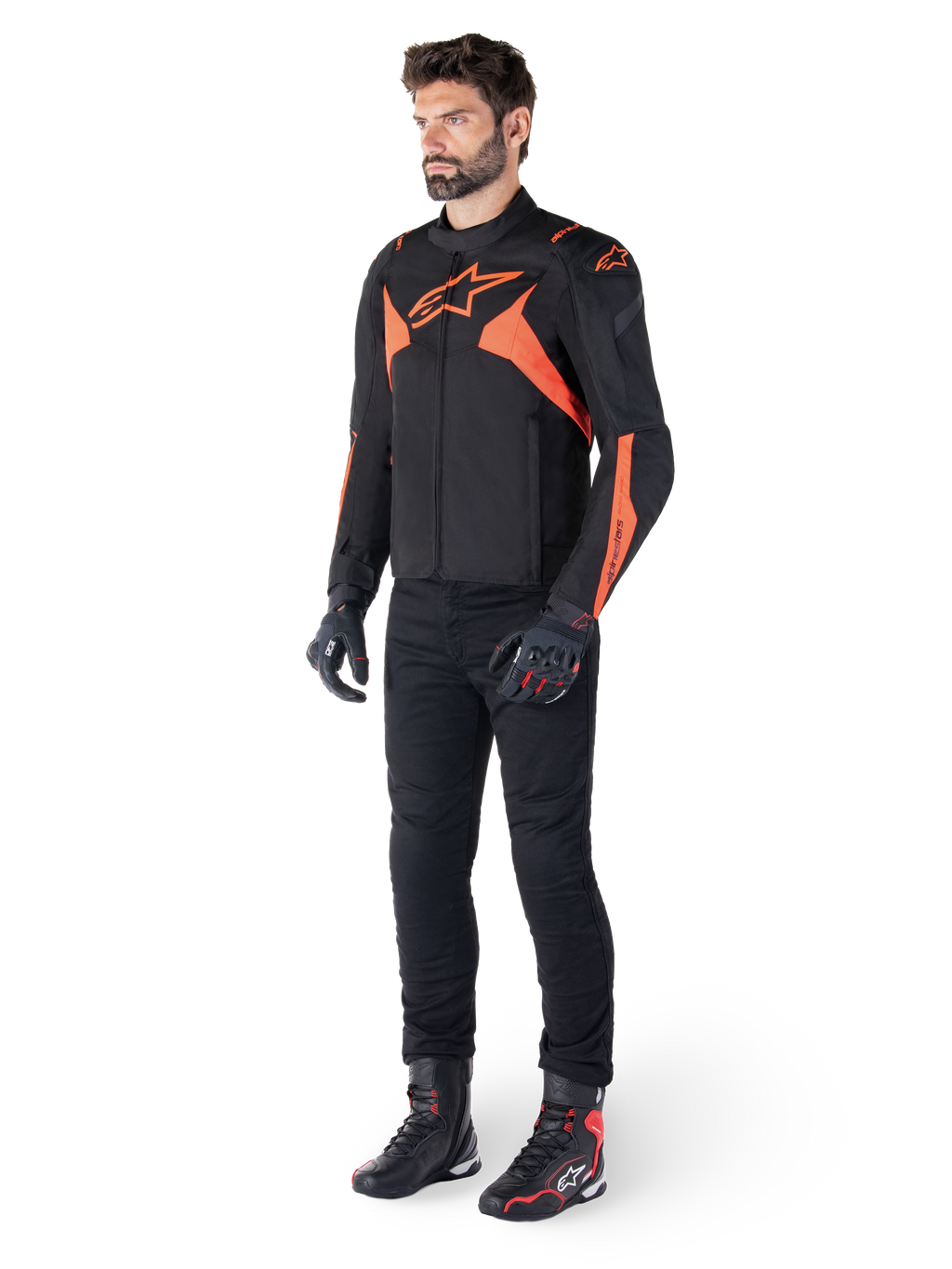 Alpinestars T-Jaws V4 Wasserdichte Jacke, Schwarz und Rot Fluo, getragen von einem männlichen Model mit schwarzer Hose, Handschuhen und Stiefeln, mit leuchtend orangefarbenen Akzenten und dem Alpinestars-Logo, sportliches Design für das Motorradfahren