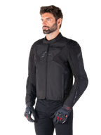 Männlicher Fahrer in der wasserdichten Alpinestars T-Jaws V4 Jacke in Schwarz, kombiniert mit einer schwarzen Hose und Schutzhandschuhen, mit einer schlanken sportlichen Passform, tonalen Alpinestars-Logos auf der Brust und den Schultern sowie einer leistungsstarken Textilkonstruktion.