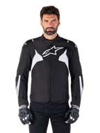 Alpinestars T-Jaws V4 Waterproof Jacket, zwart en wit, sportieve textiele motorjas voor heren, voorzien van een wit sterlogo op de borst, witte schouderaccenten en witte strepen op de onderarmen, hoge kraag, atletische pasvorm voor rijden op de weg